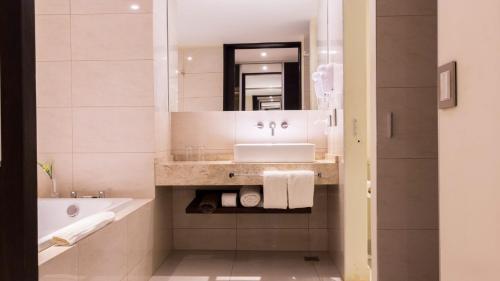 a bathroom with a sink and a tub and a mirror at Pirayu Hotel & Resort in Puerto Iguazú