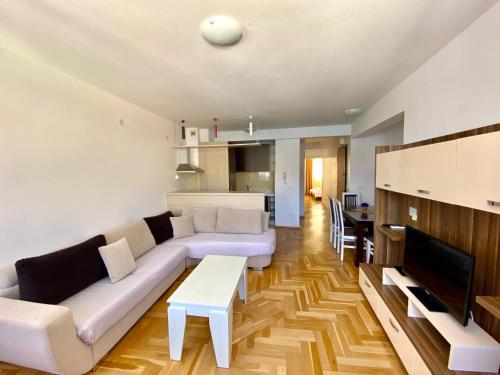 a living room with a white couch and a table at Apartments First Line in Petrovac na Moru
