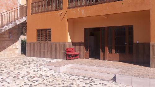 a pair of red chairs sitting outside of a building at ApartHotel Família Meireles in Luziânia
