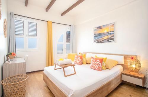 1 dormitorio con 1 cama grande con almohadas amarillas en Foyal Suites en Fort-de-France