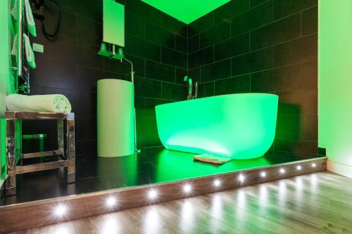 a green bath tub in a bathroom with black tiles at Atelier Montparnasse Hôtel in Paris