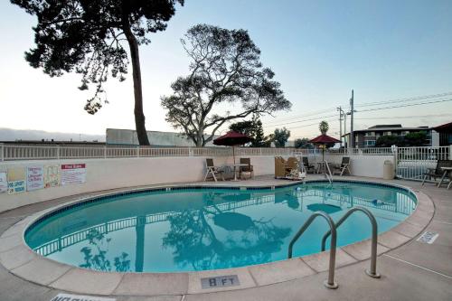 a swimming pool at a resort with tables and chairs at Motel 6-Monterey, CA in Monterey