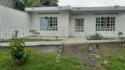 a white house with a fence in front of it at Casa piscina in Mariquita