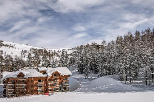 a building in the snow with snow covered trees at Résidence Pierre & Vacances l'Albane in Vars
