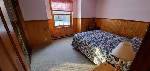 a bedroom with a bed and a window and a lamp at Motel Le Fleuron in Saint-Donat-de-Montcalm