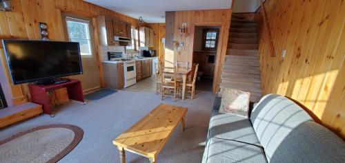 a living room with a tv and a couch and a table at Motel Le Fleuron in Saint-Donat-de-Montcalm