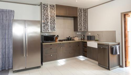 uma cozinha com armários castanhos e um frigorífico de aço inoxidável em Guinea's Rest em Waipapa