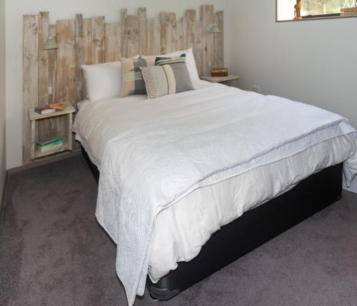 - une chambre avec un grand lit blanc et des oreillers dans l'établissement Guinea's Rest, à Waipapa