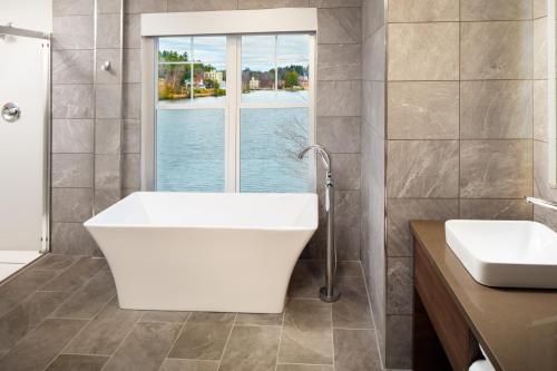a bathroom with a tub and a sink and a window at voco Saranac Lake NY - Waterfront by IHG in Saranac Lake