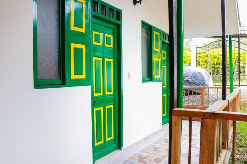 a green and yellow door on a building with a bench at Refugio El Abuelo in Santa Rosa de Cabal
