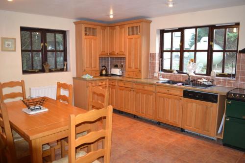 a kitchen with wooden cabinets and a wooden table with a wooden tableablish at Old Stone Cottage in Llandysul