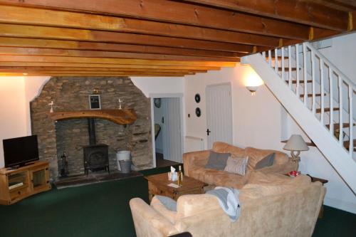 a living room with a couch and a stone fireplace at Old Stone Cottage in Llandysul