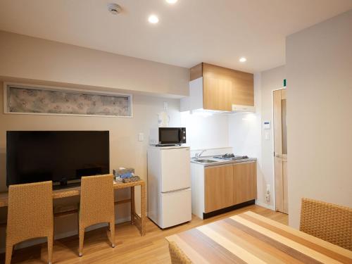 a kitchen with a small table and a white refrigerator at Tenpoint Hotel OKOU in Naha