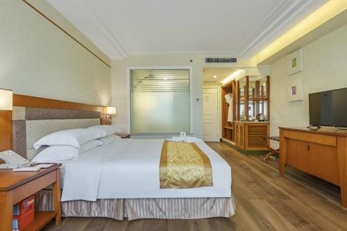una camera con un grande letto e una televisione di Haikou Jingheng Hotel - formerly the New Osrock Hotel a Haikou