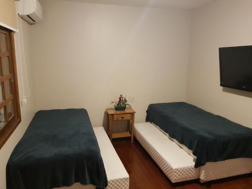 a small room with two beds and a tv at GringsApsAluguel205 in Gramado