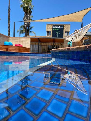 Mulwala Paradise Palms Motel في مولوالا: مسبح فيه مظله وكرسي