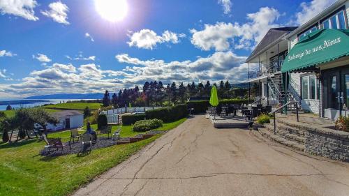 a road in front of a building with the sun in the sky at Auberge de nos Aieux in Les Éboulements