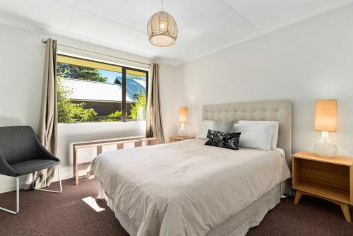 a bedroom with a bed and a window and a chair at Rees on Reid - Arrowtown Holiday Home in Arrowtown