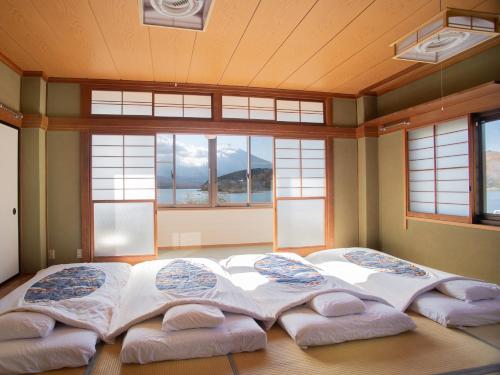 a large bed with four pillows in a room with windows at Tabist Lakeside in Fujinami Yamanakako in Yamanakako