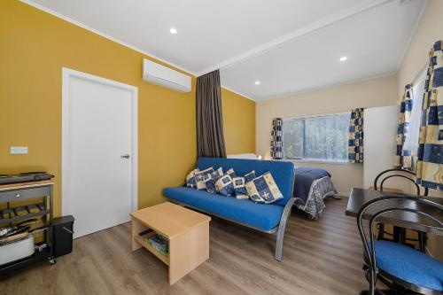 a living room with a blue couch and a window at Searenity - Waikanae Beach Holiday Home in Waikanae