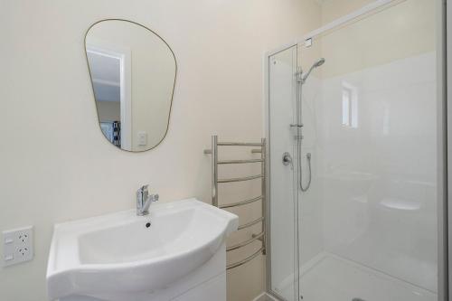 a white bathroom with a sink and a shower at Searenity - Waikanae Beach Holiday Home in Waikanae