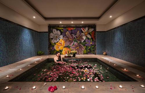 a woman sitting in a pool filled with flowers at Ninh Binh Hidden Charm Hotel & Resort in Ninh Binh
