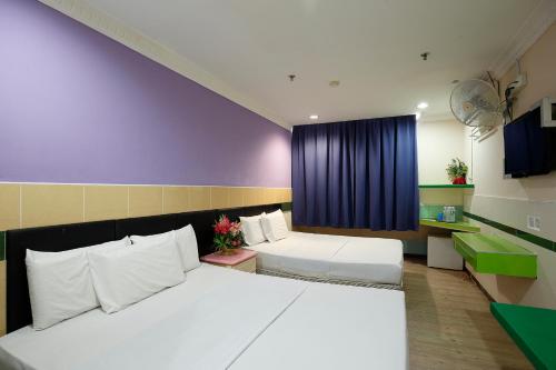 a bedroom with two beds and a blue curtain at Cosy Inn in Miri