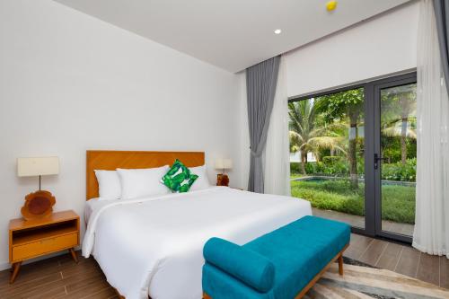 a bedroom with a white bed and a large window at Le Palmier Ho Tram Resort - Beachfront with Private Beach in Ho Tram