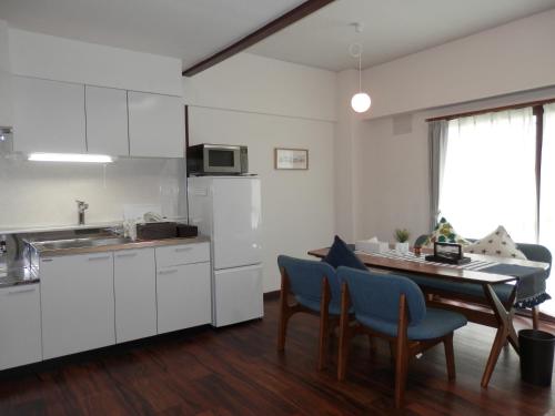 uma cozinha com armários brancos e uma mesa com cadeiras azuis em Maple Sumikawa #201 em Sapporo