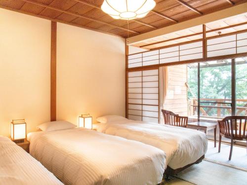 a room with three beds and a window at HOTEL SHIRAHAMAKAN in Shirahama