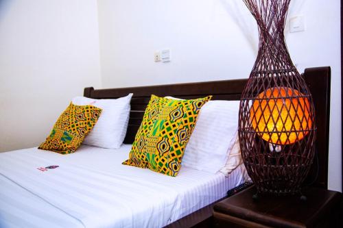 Un dormitorio con una cama con almohadas de colores y una lámpara. en Cypa Hotel, en Abiyán