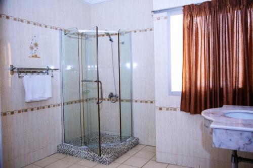 uma casa de banho com um chuveiro e um lavatório. em Cypa Hotel em Abidjan