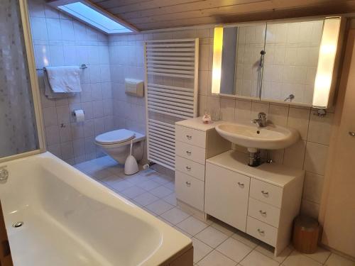 een badkamer met een bad, een wastafel en een toilet bij Maison Chalet in Grandfontaine