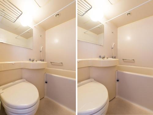 a bathroom with a toilet and a sink and a mirror at Tabist Hotel Tetora Kitakyushu in Kitakyushu