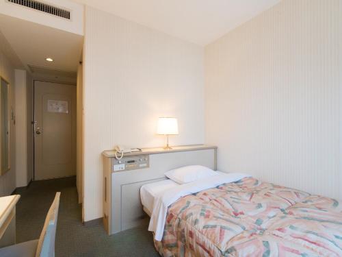 a bedroom with a bed with a lamp on it at Tabist Hotel Tetora Kitakyushu in Kitakyushu