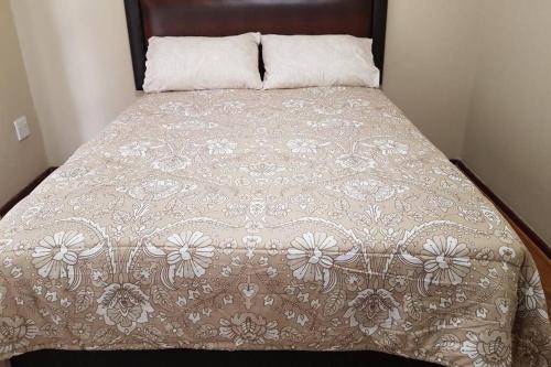 a bed with a brown and white comforter at Holiday Home in Port Elizabeth