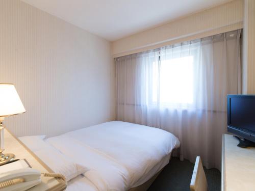 a hotel room with a bed and a television at Tabist Hotel Tetora Kitakyushu in Kitakyushu
