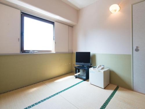 an empty room with a tv and a window at Tabist Hotel Tetora Kitakyushu in Kitakyushu