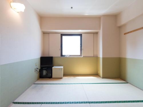 an empty room with a television and a window at Tabist Hotel Tetora Kitakyushu in Kitakyushu