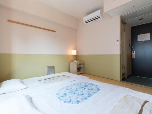 a bedroom with a large white bed with blue flowers at Tabist Hotel Tetora Kitakyushu in Kitakyushu