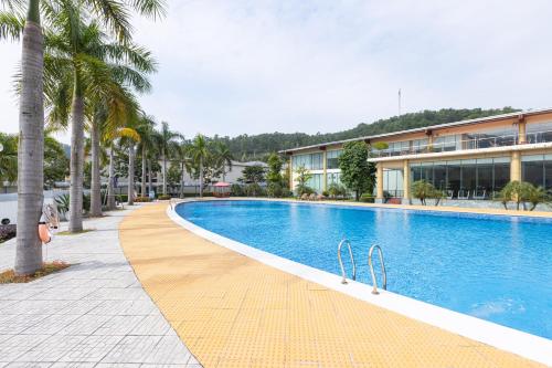 a swimming pool with palm trees in front of a building at Anh Phát Resort in Tĩnh Gia