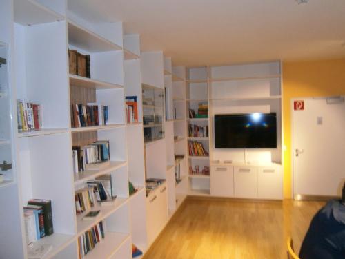 a living room with white bookshelves and a tv at Institut St.Sebastian in Salzburg