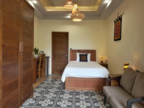 a bedroom with a bed and a couch at Pink Tulip Hoi An in Hoi An