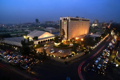 duży budynek z samochodami zaparkowanymi na parkingu w obiekcie Pearl Continental Hotel, Karachi w mieście Karaczi