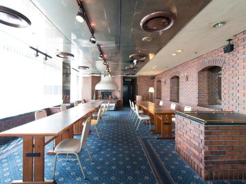 a restaurant with wooden tables and chairs and a brick wall at Tabist Hotel Tetora Kitakyushu in Kitakyushu