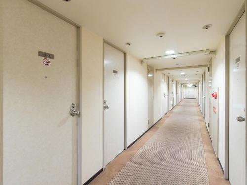an empty corridor of an office building with white doors at Tabist Hotel Tetora Kitakyushu in Kitakyushu
