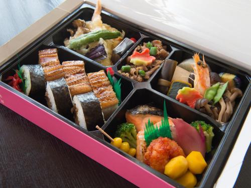 a pink lunch box filled with different types of food at Tabist Hotel Tetora Kitakyushu in Kitakyushu