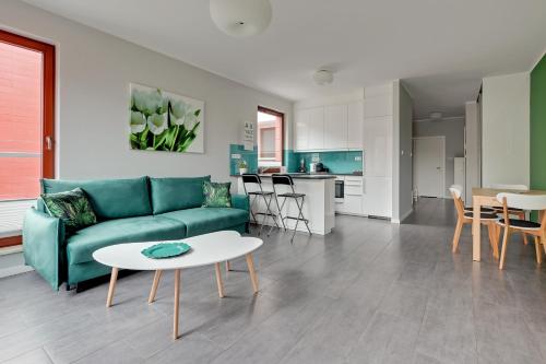 a living room with a green couch and a table at Garnizon Apartments & Free Parking by Downtown Apartments in Gdańsk
