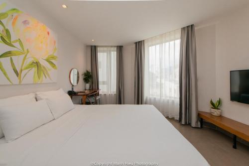 a bedroom with a large white bed and a television at Mojzo Inn Boutique Hotel in Nha Trang