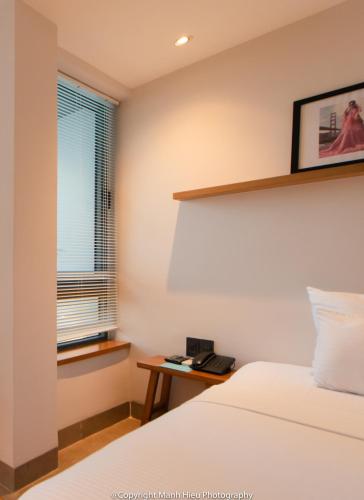 a bedroom with a bed and a window and a telephone at Mojzo Inn Boutique Hotel in Nha Trang
